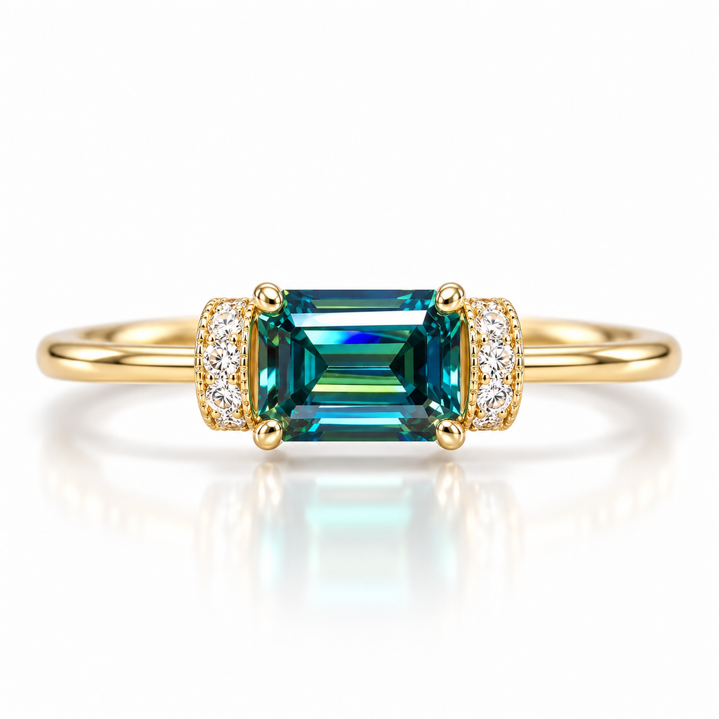 1 carat lab-created green moissanite ring featuring a horizontally set 5x7mm emerald-cut gemstone with teal-green reflections, four gold-tone prongs, and sparkling cubic zirconia side accents in Gold Plated 925 sterling silver on a white background.