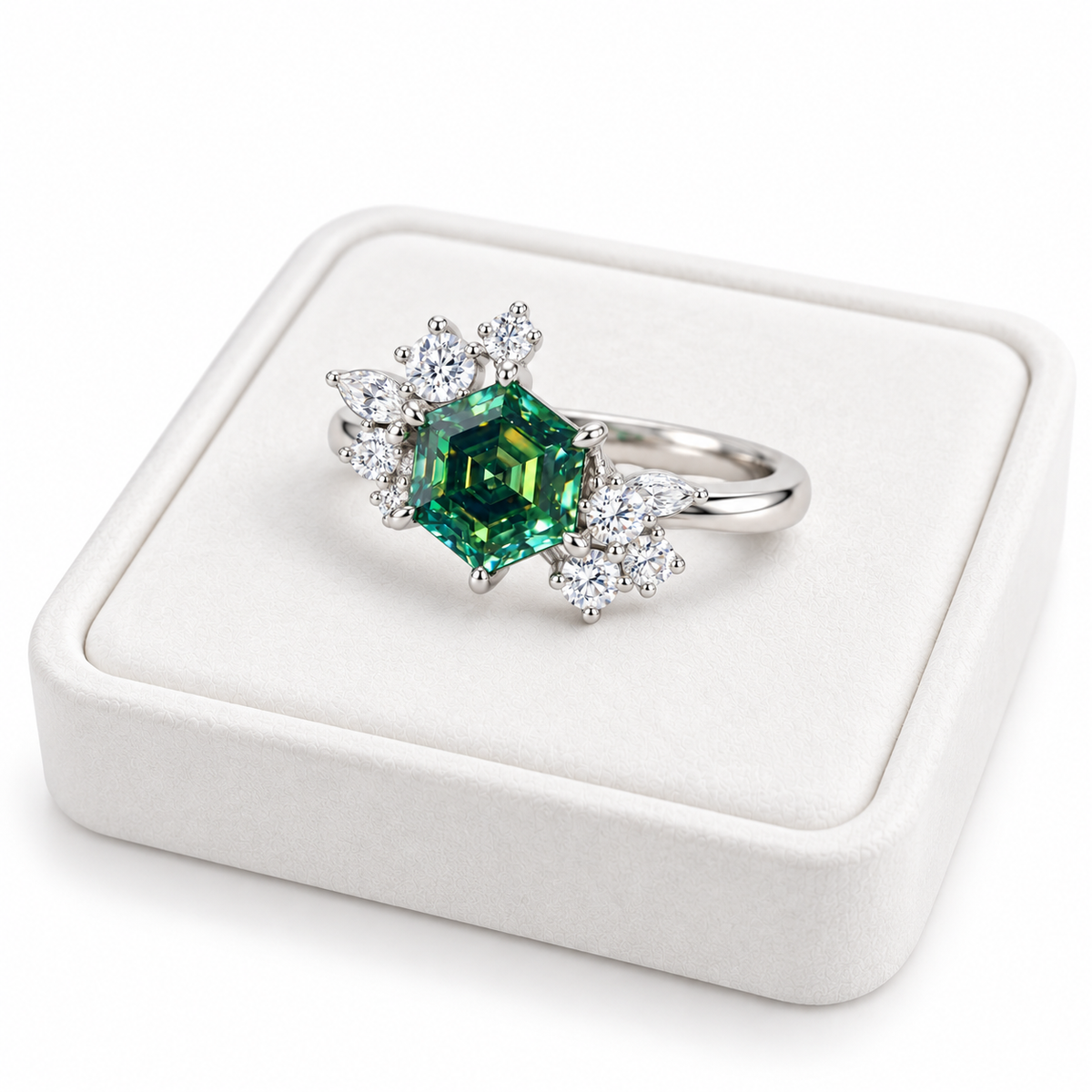 Three-quarter angle photograph of a 1 carat green moissanite ring resting on a white velvet jewelry tray, highlighting the 6mm hexagon-cut gemstone, asymmetrical floral cubic zirconia clusters, and Platinum Plated sterling silver setting.