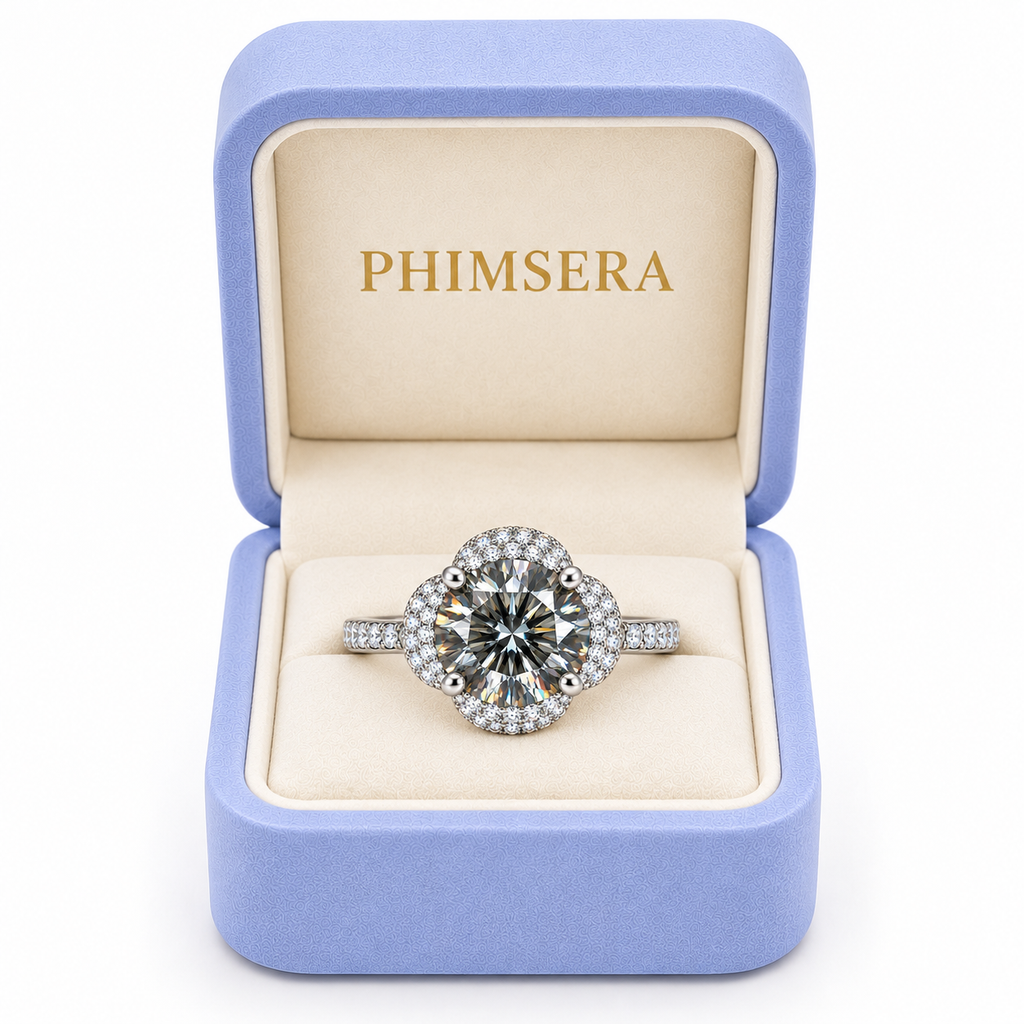 Two carat gray moissanite floral halo ring displayed inside a periwinkle Phimsera jewelry gift box with an ivory interior and gold PHIMSERA lettering against a pure white background.