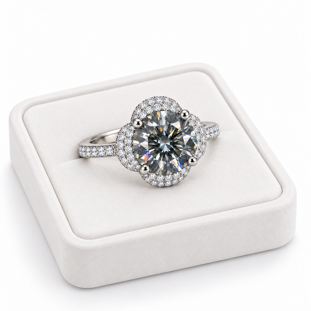 Angled view of an 8mm gray moissanite floral halo ring resting on a turned white velvet jewelry tray, highlighting the four-petal cubic zirconia halo and pavé sterling silver band.
