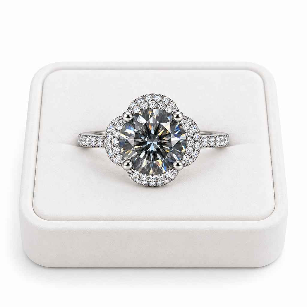 Two carat round brilliant gray moissanite floral halo ring displayed on a premium white velvet jewelry tray against a pure white background, showing the gray center gemstone and sparkling cubic zirconia setting.