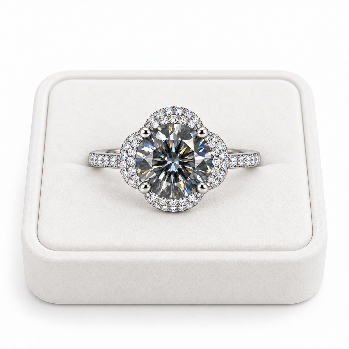 Two carat round brilliant gray moissanite floral halo ring displayed on a premium white velvet jewelry tray against a pure white background, showing the gray center gemstone and sparkling cubic zirconia setting.
