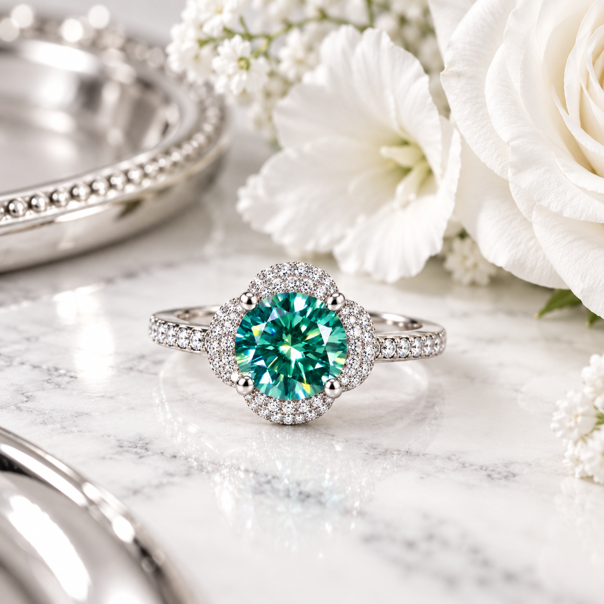 2 carat round brilliant green moissanite floral halo ring displayed on elegant white marble with subtle silver-gray veining, delicate white flowers, and soft silver accents, showcasing the vibrant 8mm teal-green gemstone and sparkling cubic zirconia floral setting.