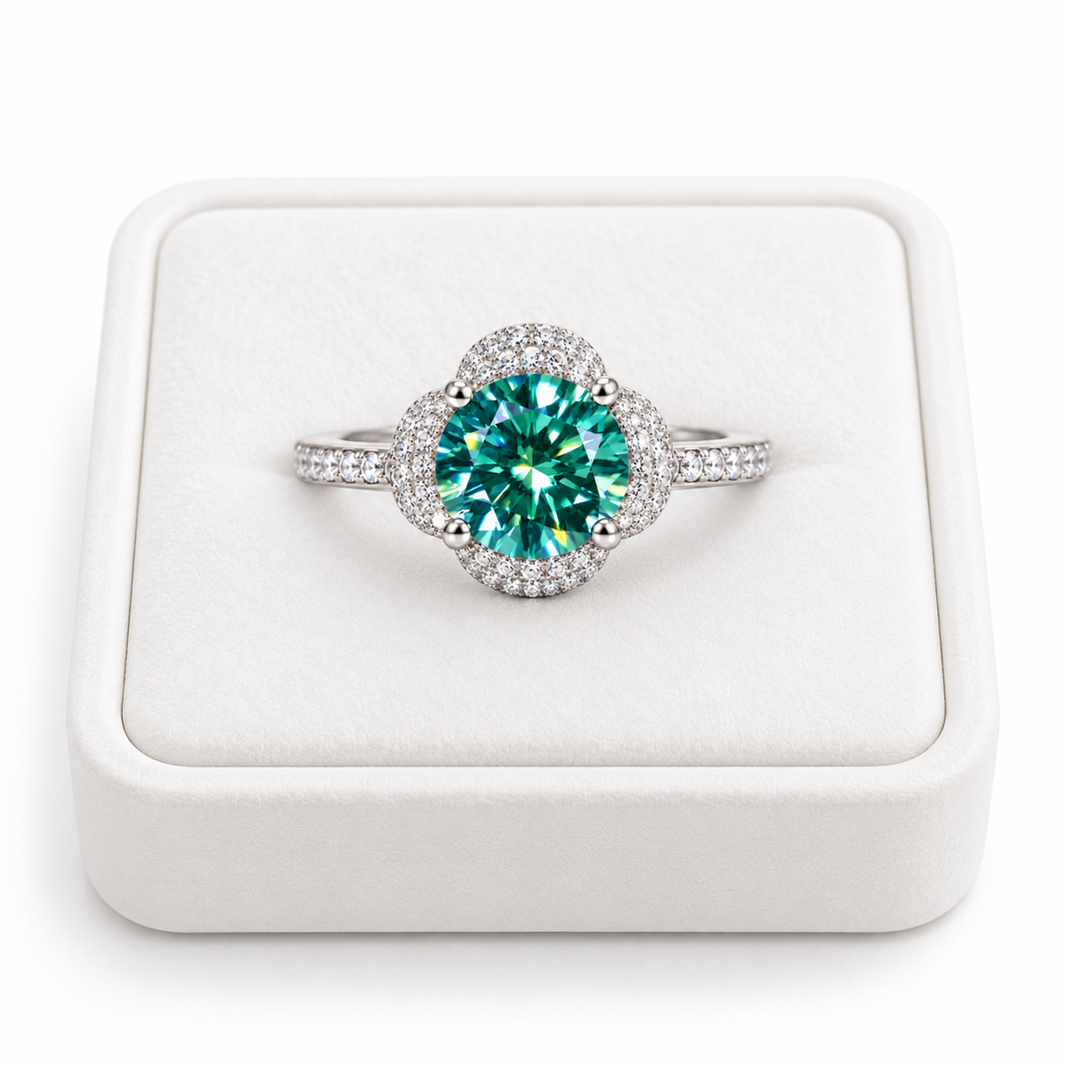 2 carat 8mm round brilliant green moissanite floral halo ring displayed on a premium white velvet jewelry tray against a pure white background, featuring a vibrant teal-green gemstone, sparkling four-petal cubic zirconia halo, and elegant sterling silver band.