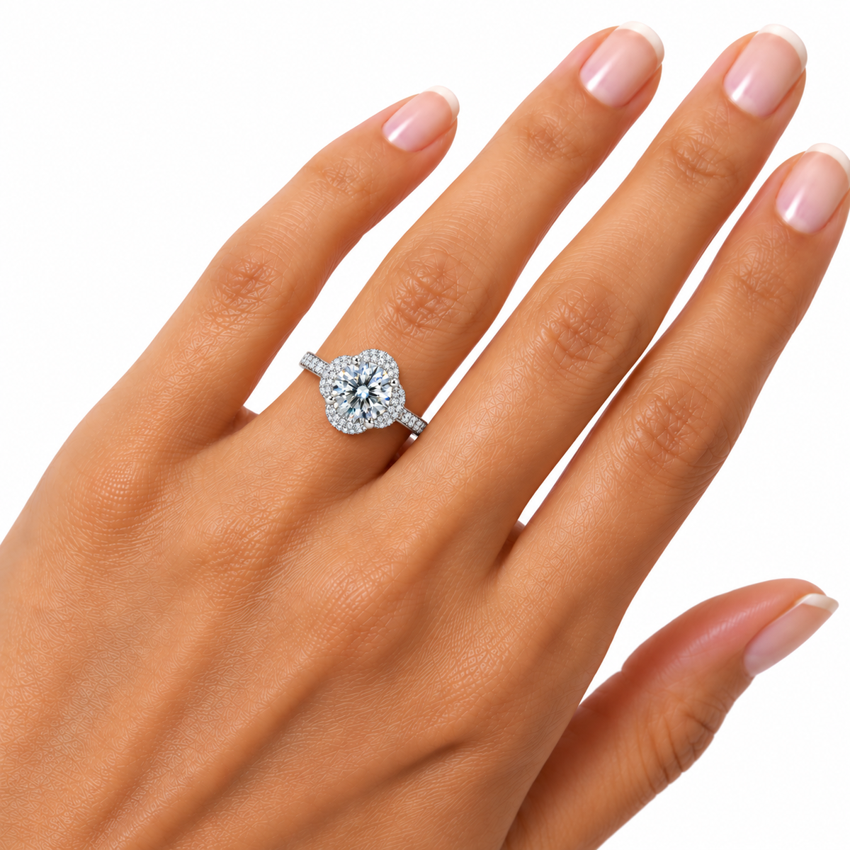White moissanite floral halo ring displayed on a woman's ring finger in an alternate hand pose, featuring an 8mm round brilliant gemstone, four-petal halo and elegant sterling silver band.