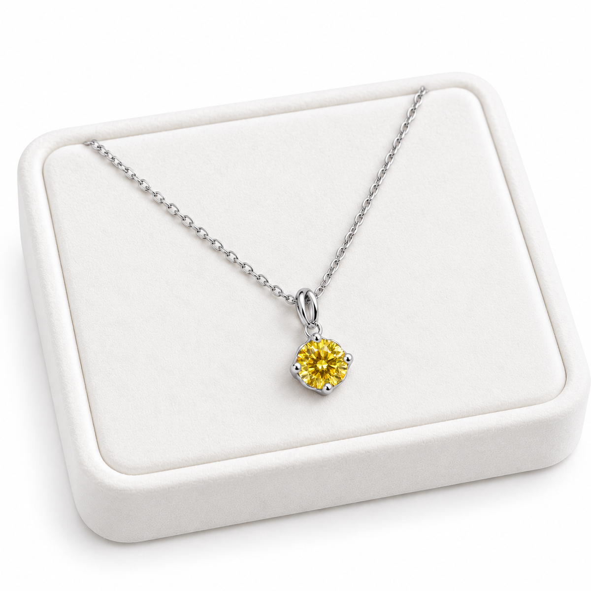 Angled white velvet jewelry tray displaying an 8mm round brilliant yellow moissanite pendant necklace with a four-prong sterling silver setting, delicate oval-link chain, and clean white background.