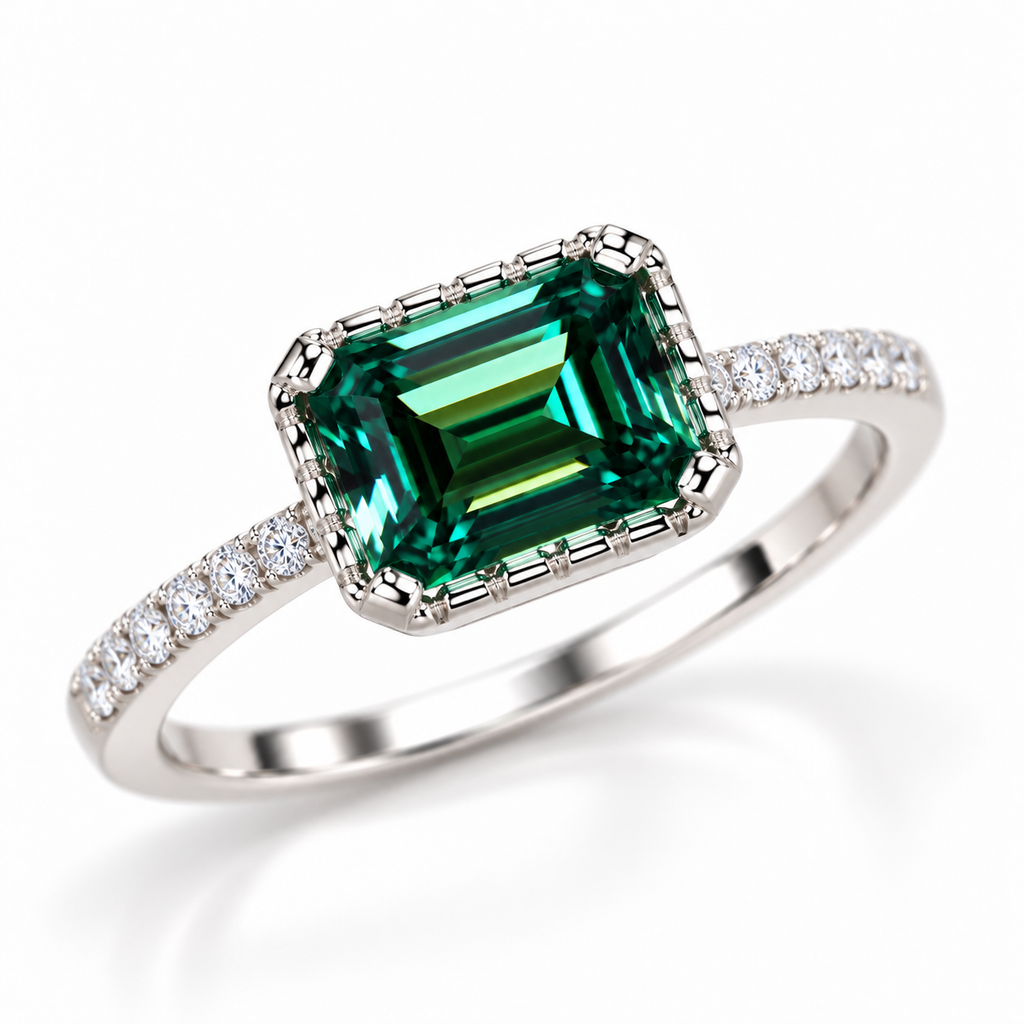 Three-quarter view of a 2 carat green moissanite ring featuring an elongated 6x8mm emerald-cut gemstone, polished geometric four-prong setting, and sparkling cubic zirconia shoulder accents in Platinum Plated sterling silver.
