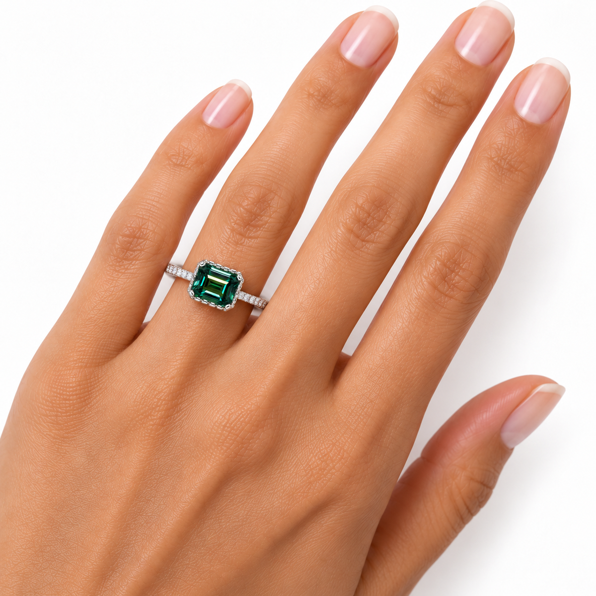 2 carat lab-created green moissanite ring worn on a woman's ring finger, displaying realistic 6x8mm emerald-cut gemstone proportions, rich forest-green and teal reflections, and sparkling cubic zirconia accents in sterling silver.