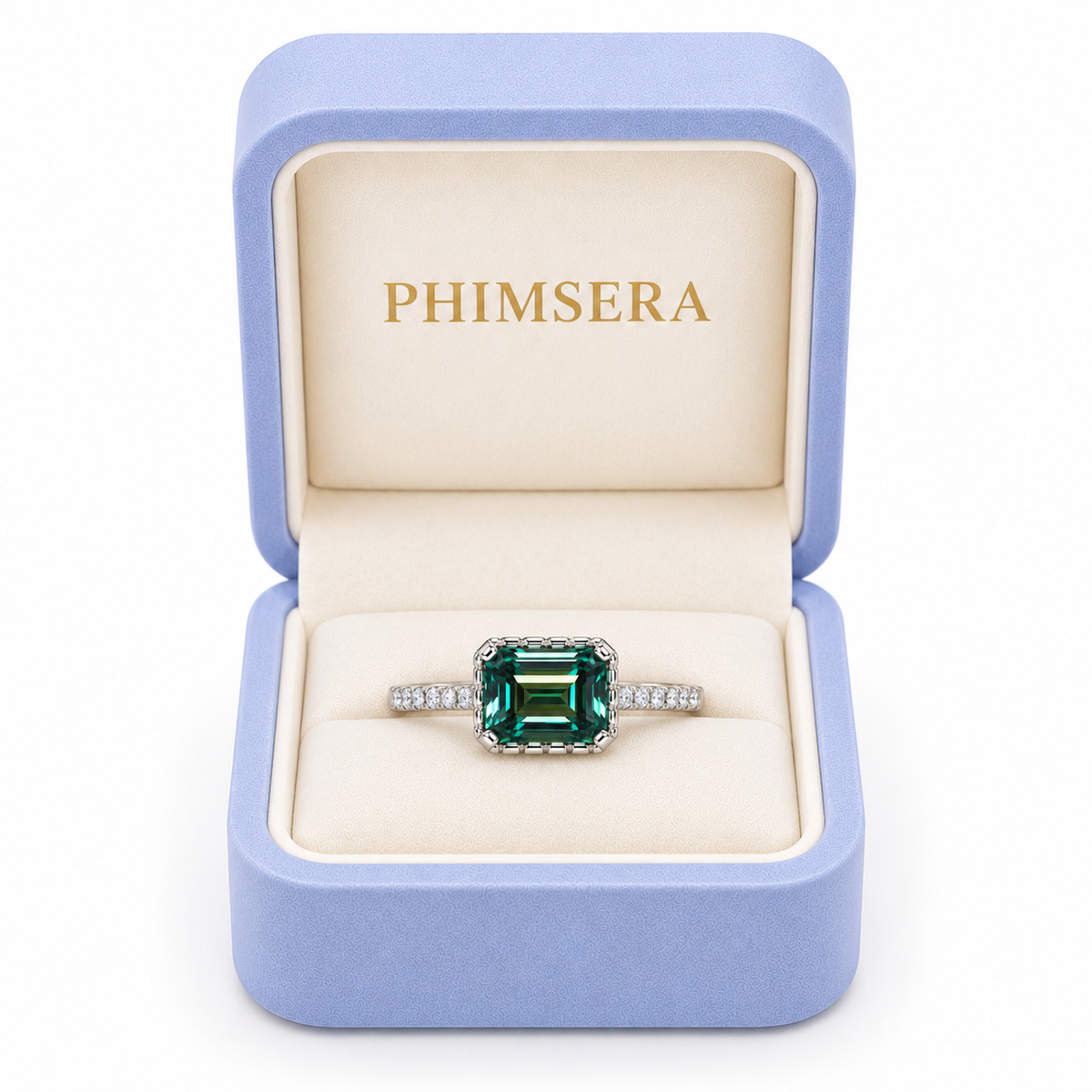 2 carat lab-created green moissanite ring displayed inside a periwinkle Phimsera jewelry box with cream velvet interior and gold PHIMSERA lettering, featuring a 6x8mm emerald-cut gemstone and sparkling cubic zirconia accents.