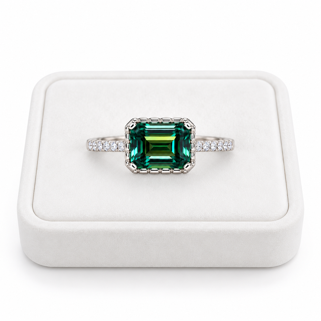 2 carat green moissanite ring featuring a 6x8mm horizontally set emerald-cut gemstone displayed on a flat white velvet jewelry tray against a pure white background, highlighting the deep green color and sparkling cubic zirconia accents.