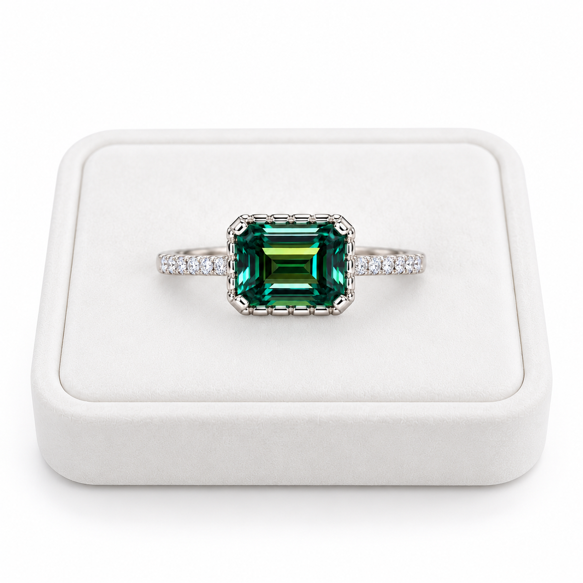2 carat green moissanite ring featuring a 6x8mm horizontally set emerald-cut gemstone displayed on a flat white velvet jewelry tray against a pure white background, highlighting the deep green color and sparkling cubic zirconia accents.