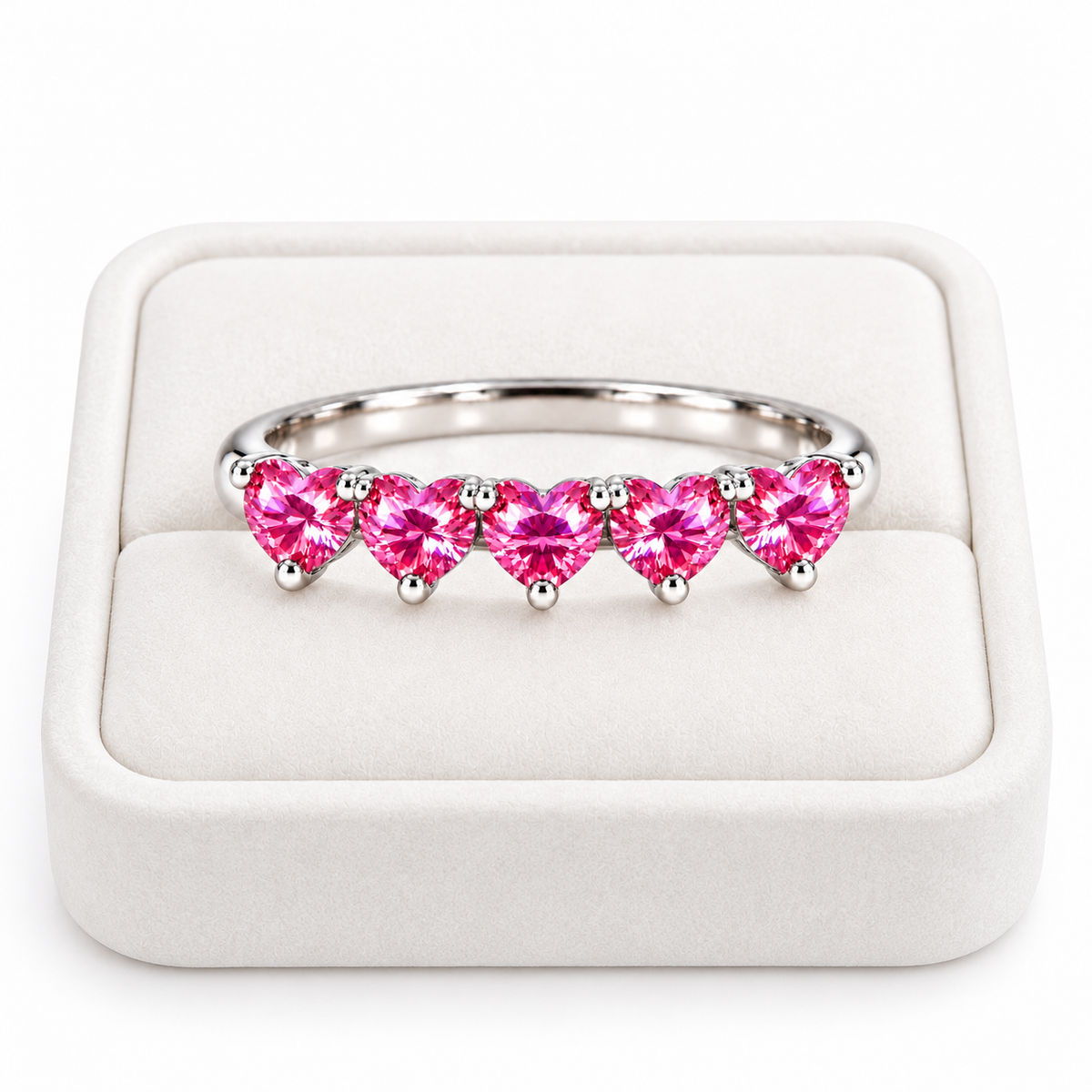 Five 4mm heart-cut pink moissanite ring displayed on a white velvet jewelry tray