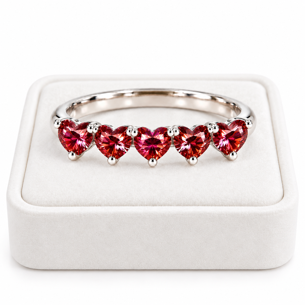 Five 4mm heart-cut red moissanite ring displayed on a white velvet jewelry tray