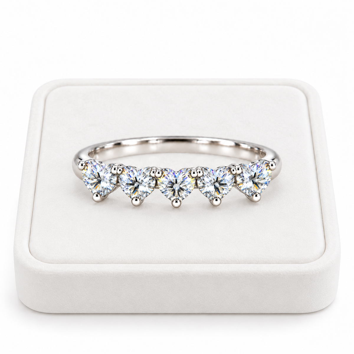 Five 4mm heart-cut white moissanite ring displayed on a white velvet jewelry tray