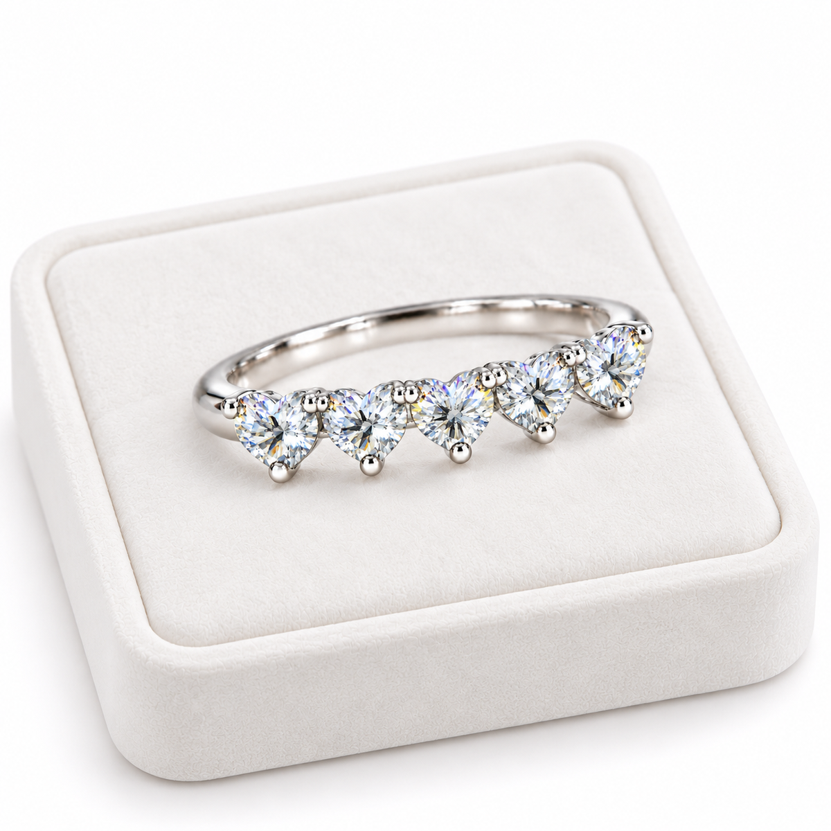 Angled five-heart white moissanite ring displayed on a white velvet jewelry tray