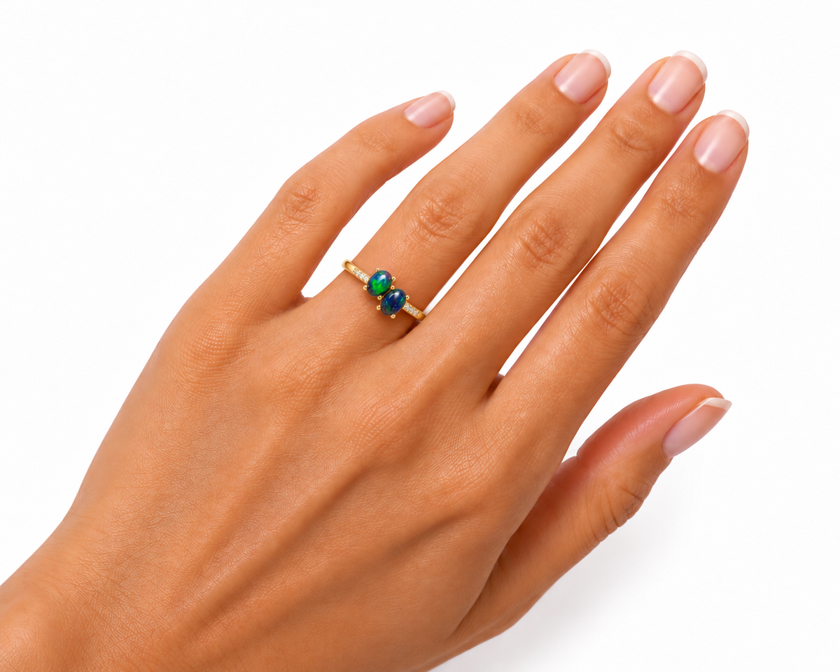 Black fire opal two-stone ring worn on a woman's ring finger, showing the realistic proportions of two 4x5mm oval gemstones, colorful blue-green flashes, and delicate Gold Plated sterling silver band.