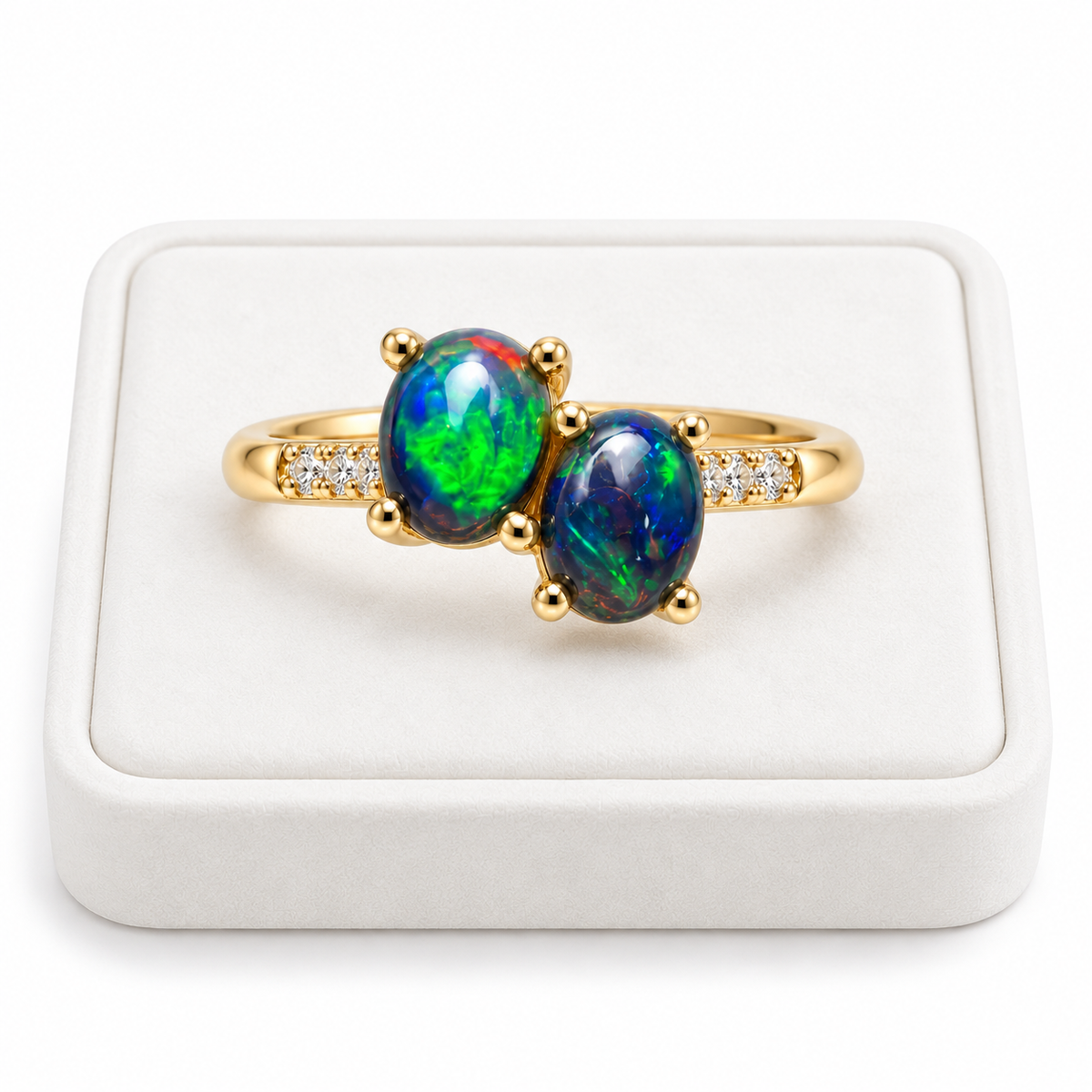 Black fire opal two-stone ring with oval gemstones displayed on a flat white velvet jewelry tray against a bright white background.