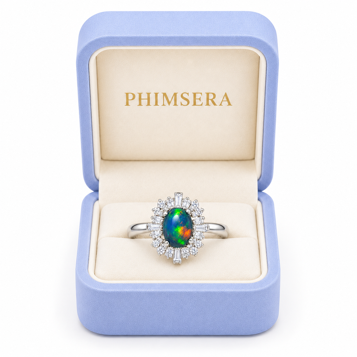 Black opal sunburst halo ring displayed inside a periwinkle Phimsera jewelry box with cream velvet interior and gold PHIMSERA lettering.