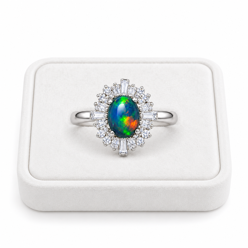 Black opal sunburst halo ring with a 5x7mm oval gemstone displayed on a flat white velvet jewelry tray against a clean white background.