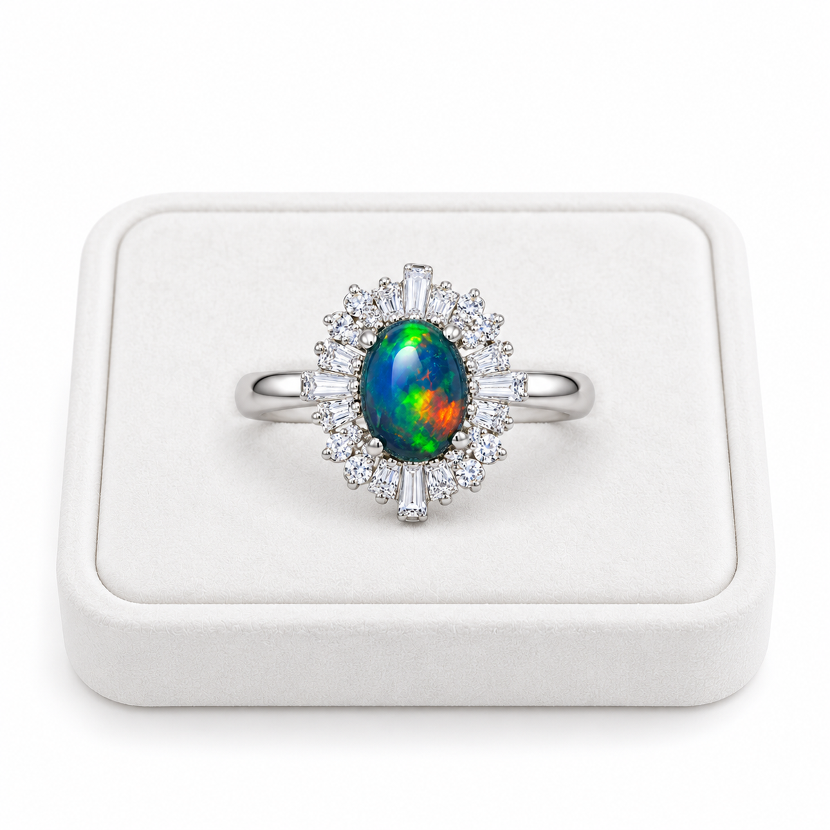 Black opal sunburst halo ring with a 5x7mm oval gemstone displayed on a flat white velvet jewelry tray against a clean white background.