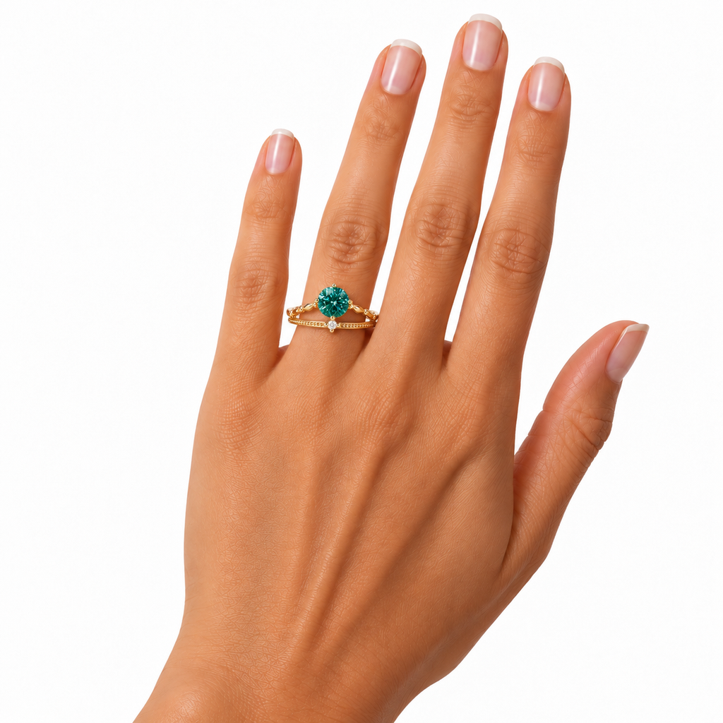 6.5mm lab-created green moissanite ring worn naturally on a woman's ring finger, featuring a true-to-size round brilliant teal-green gemstone, delicate gold-tone split-shank band, and sparkling clear cubic zirconia accent against a white background.