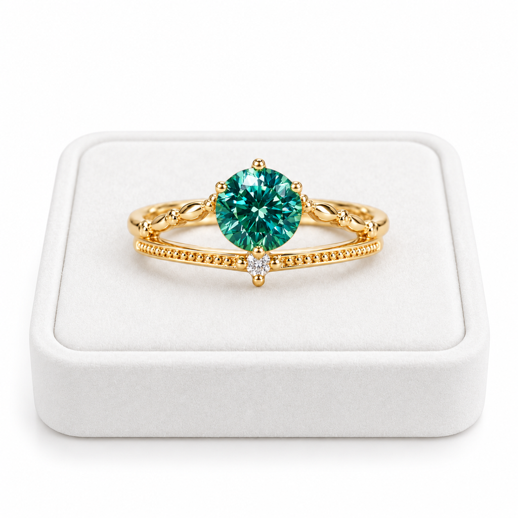 6.5mm round brilliant lab-created green moissanite ring displayed on a premium white velvet jewelry tray against a pure white background, featuring a vibrant teal-green gemstone, elegant gold-tone split-shank band, and sparkling cubic zirconia accent.