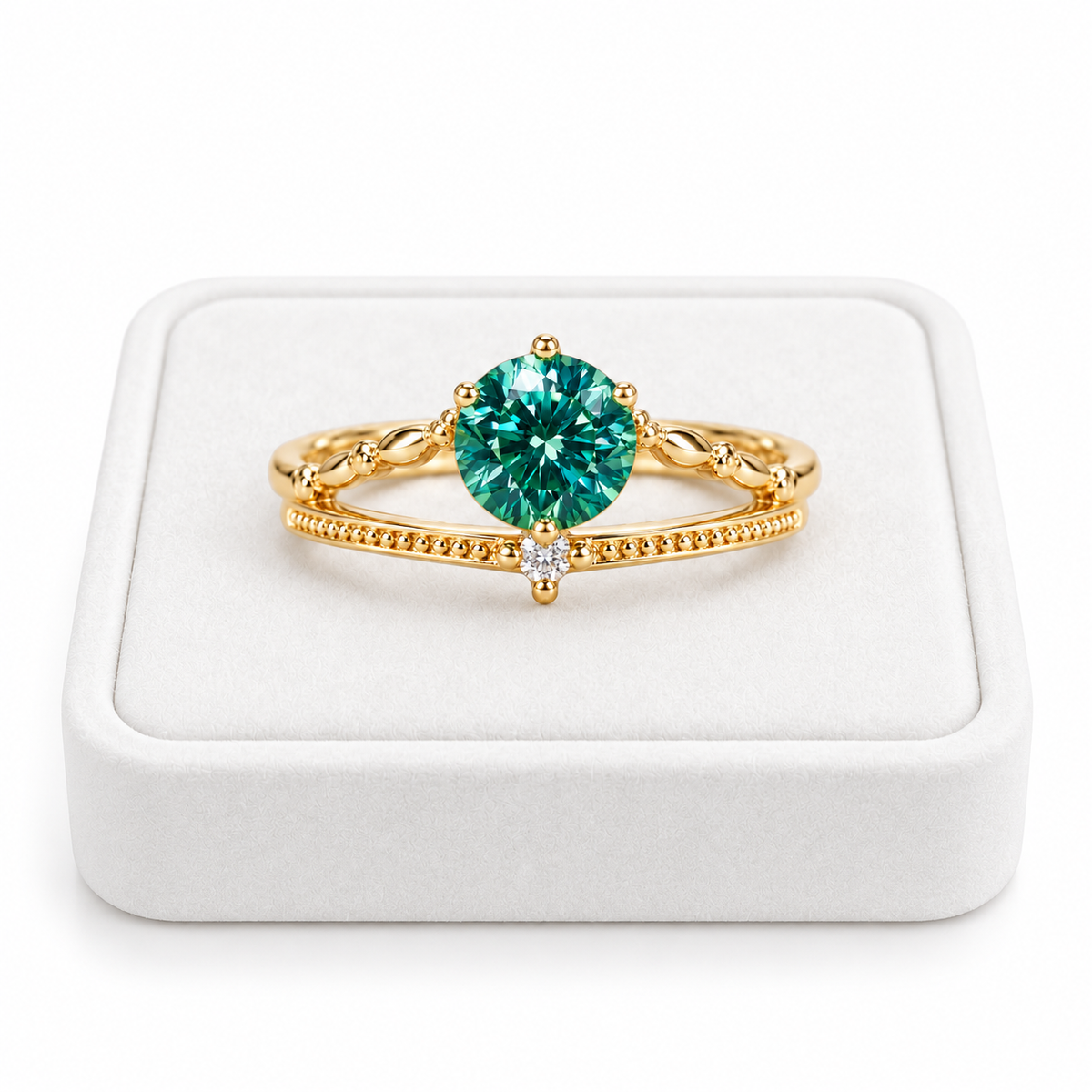 6.5mm round brilliant lab-created green moissanite ring displayed on a premium white velvet jewelry tray against a pure white background, featuring a vibrant teal-green gemstone, elegant gold-tone split-shank band, and sparkling cubic zirconia accent.