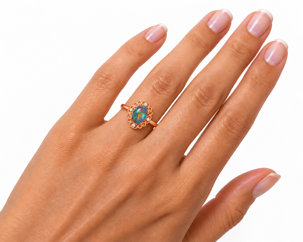 Australian black fire opal vintage filigree ring worn on a woman's ring finger, showing realistic 6x8mm oval gemstone proportions, ornate rose gold scrollwork, and delicate cubic zirconia accents.