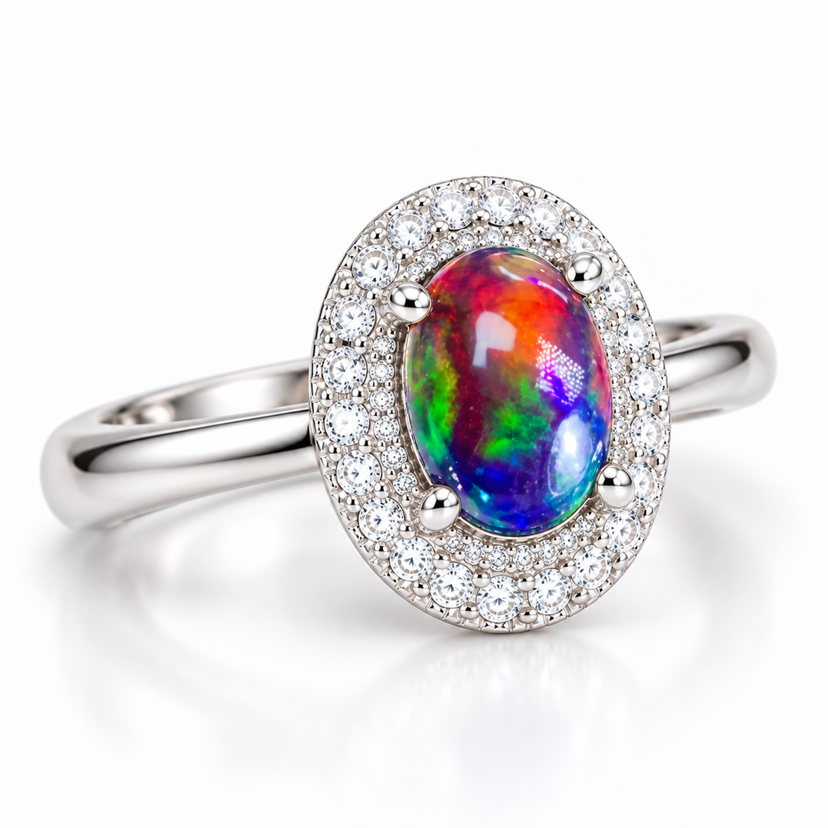 Angled product photograph of an oval Australian black fire opal ring featuring a 6x8mm dyed gemstone, rounded prongs, double CZ halo, and Platinum Plated sterling silver setting.