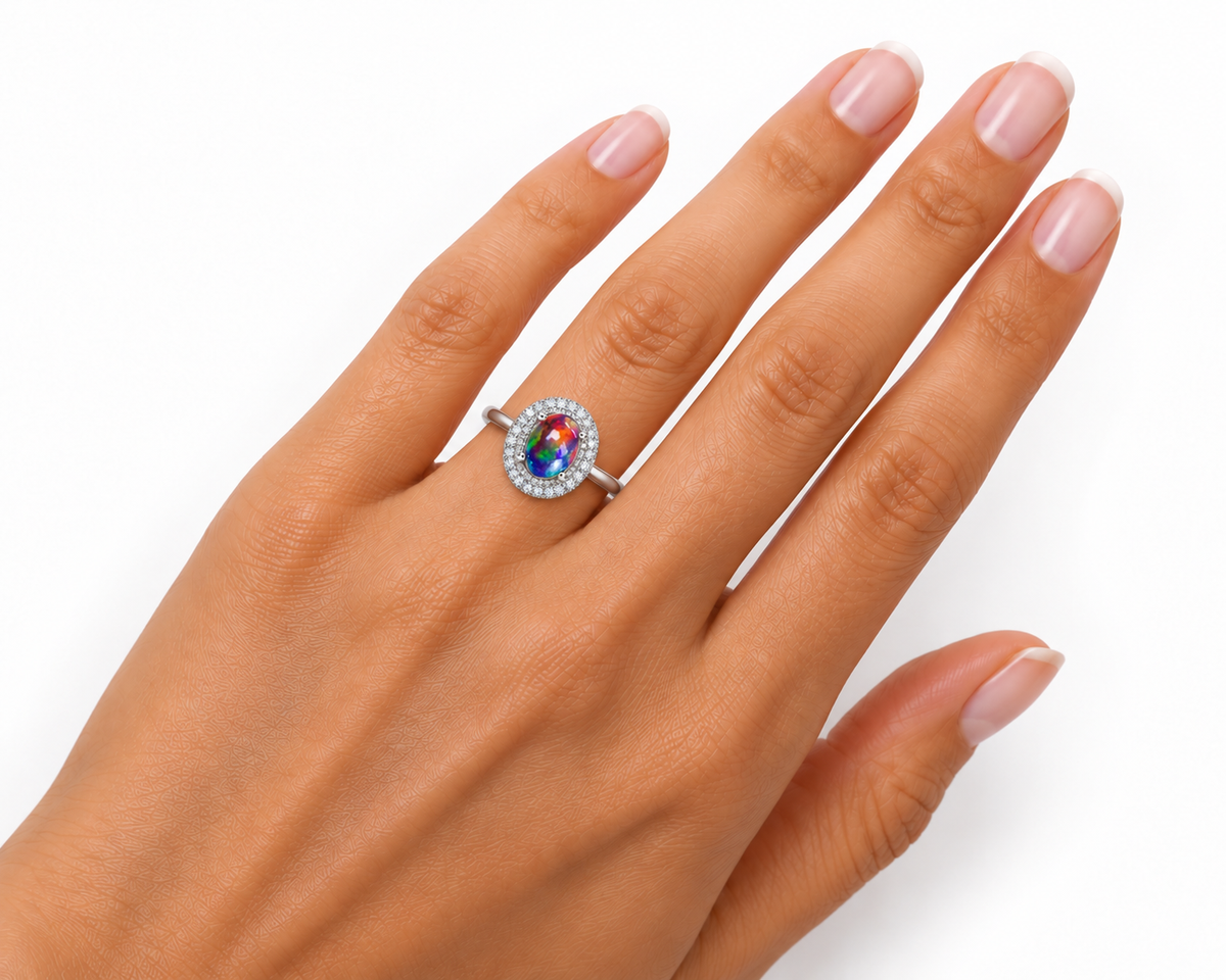 Australian black fire opal halo ring worn on a woman's ring finger, showing realistic 6x8mm oval gemstone proportions, sparkling cubic zirconia double halo, and polished silver band.