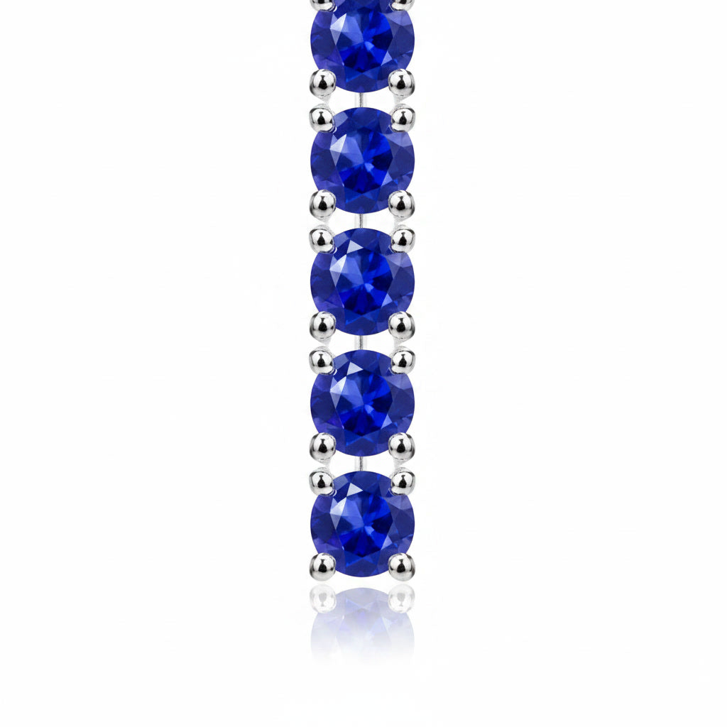 Macro view of 3mm round blue sapphire gemstones in Phimsera sterling silver dangle earrings
