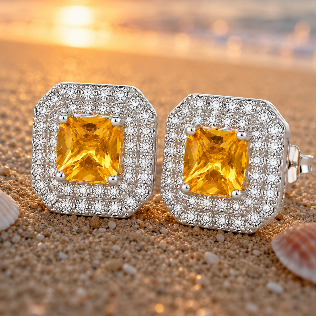 Macro lifestyle photograph of golden citrine halo earrings on sand at sunset