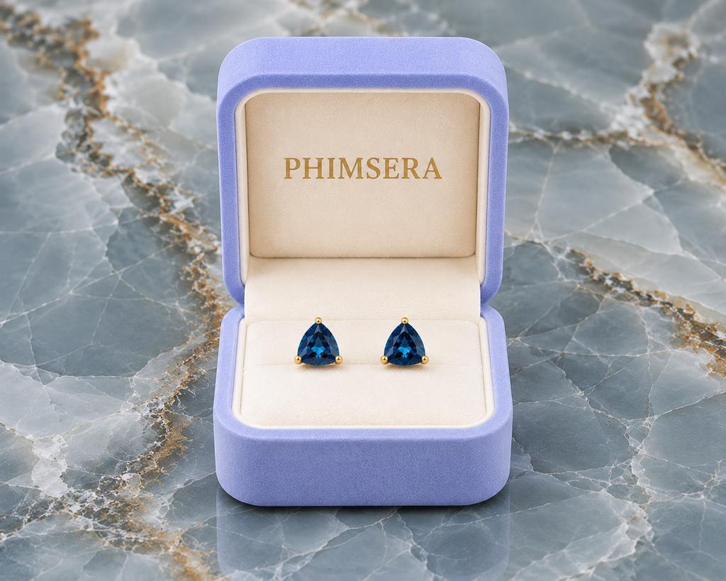 Natural 7mm trillion-cut London Blue Topaz stud earrings in solid 925 sterling silver with classic three-prong settings on a white background