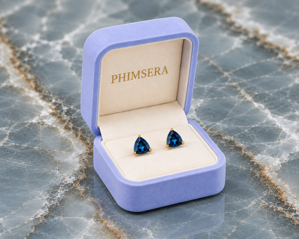 Natural 7mm trillion-cut London Blue Topaz stud earrings in solid 925 sterling silver with classic three-prong settings on a white background
