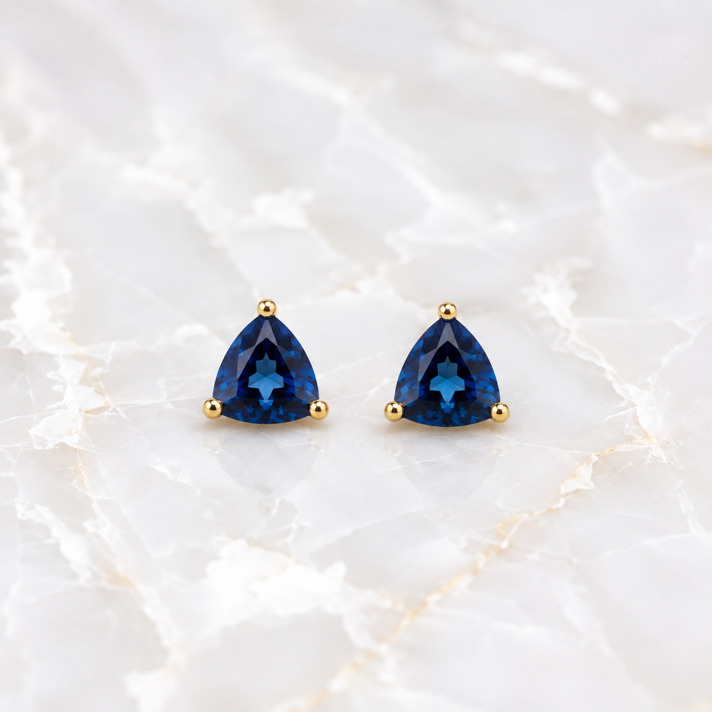 Natural 7mm trillion-cut London Blue Topaz stud earrings in solid 925 sterling silver with classic three-prong settings on a white background
