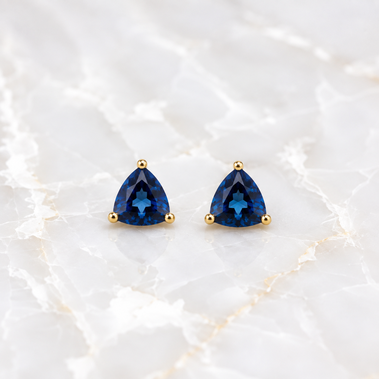 Natural 7mm trillion-cut London Blue Topaz stud earrings in solid 925 sterling silver with classic three-prong settings on a white background