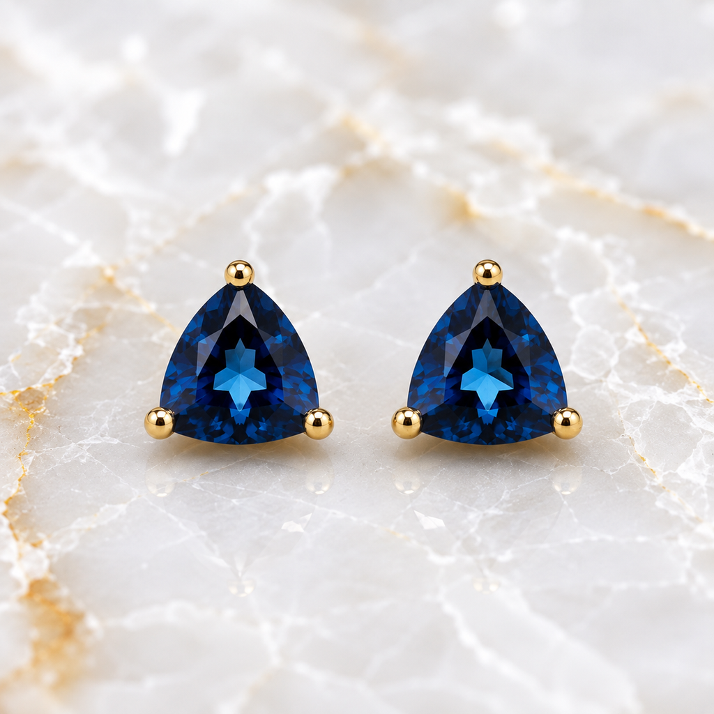 Natural 7mm trillion-cut London Blue Topaz stud earrings in solid 925 sterling silver with classic three-prong settings on a white background