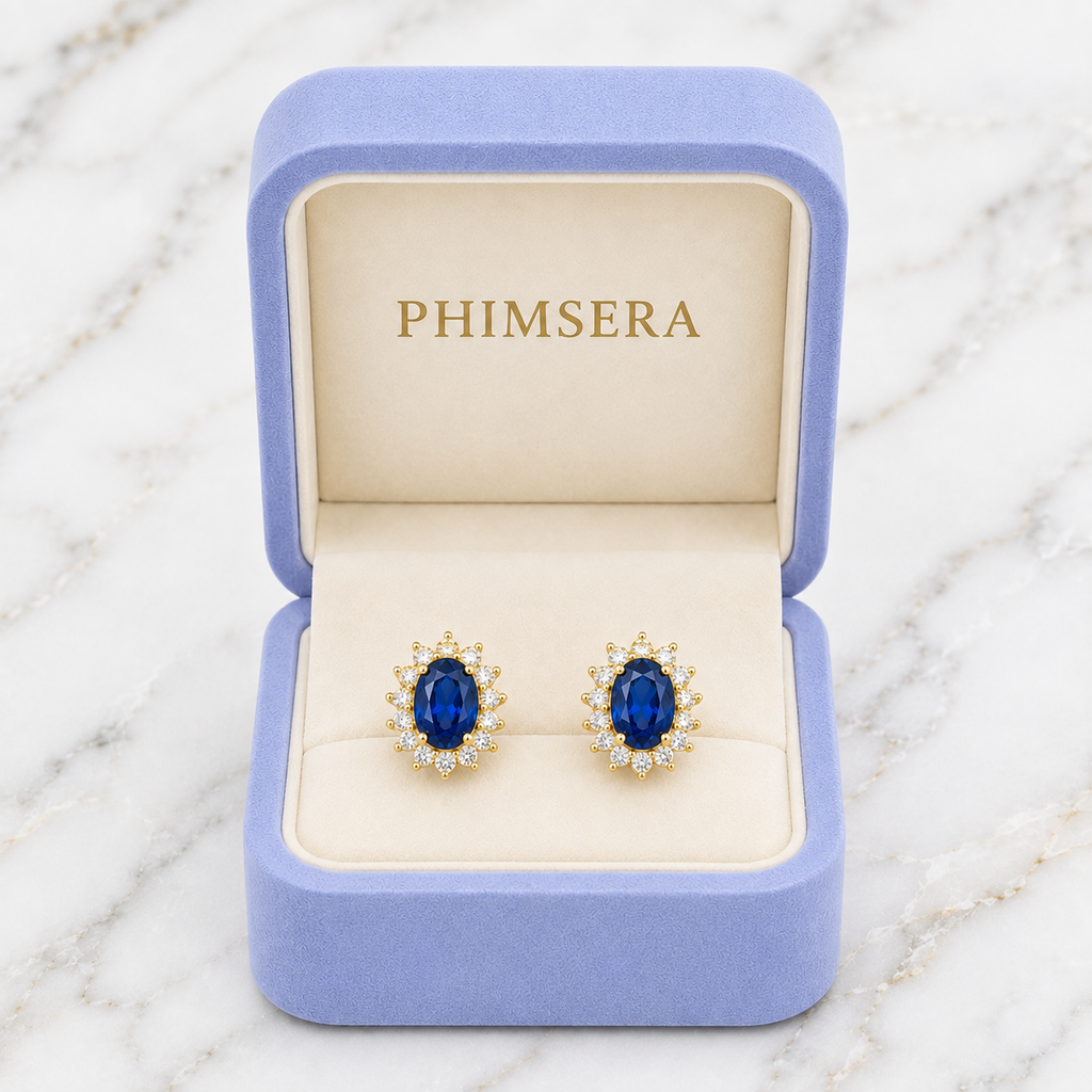 Natural 6x8mm oval London Blue Topaz halo stud earrings in solid 925 sterling silver, available in platinum, yellow gold, or rose gold finish, presented in a PHIMSERA gift box.
