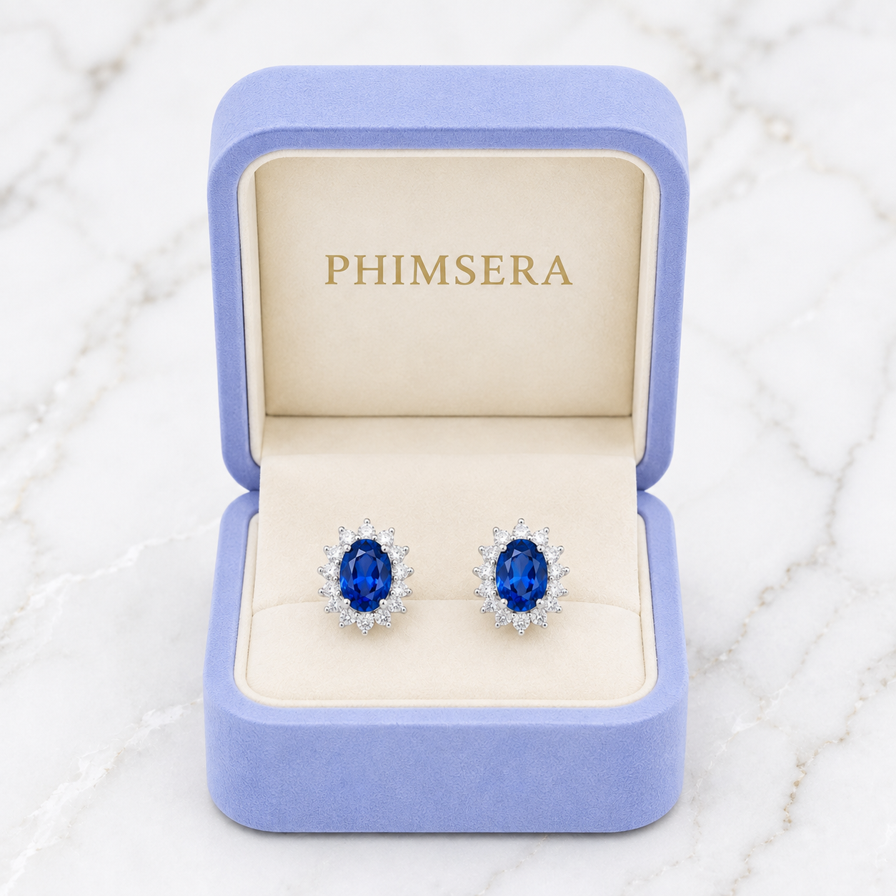 Natural 6x8mm oval London Blue Topaz halo stud earrings in solid 925 sterling silver, available in platinum, yellow gold, or rose gold finish, presented in a PHIMSERA gift box.