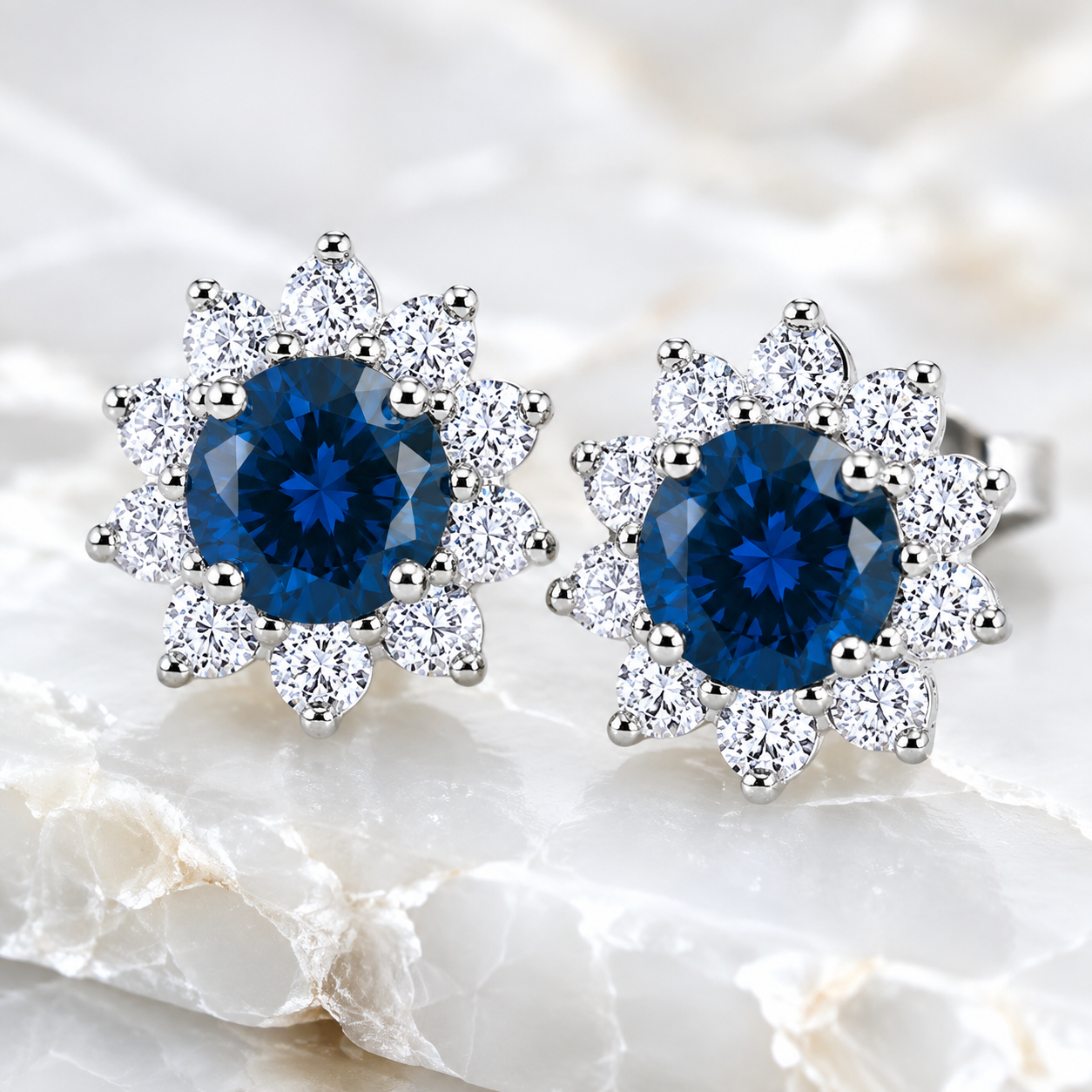 PHIMSERA Natural 5mm round London Blue Topaz floral halo stud earrings in solid 925 sterling silver with platinum plating, available in yellow gold or rose gold plating, presented in a PHIMSERA gift box.