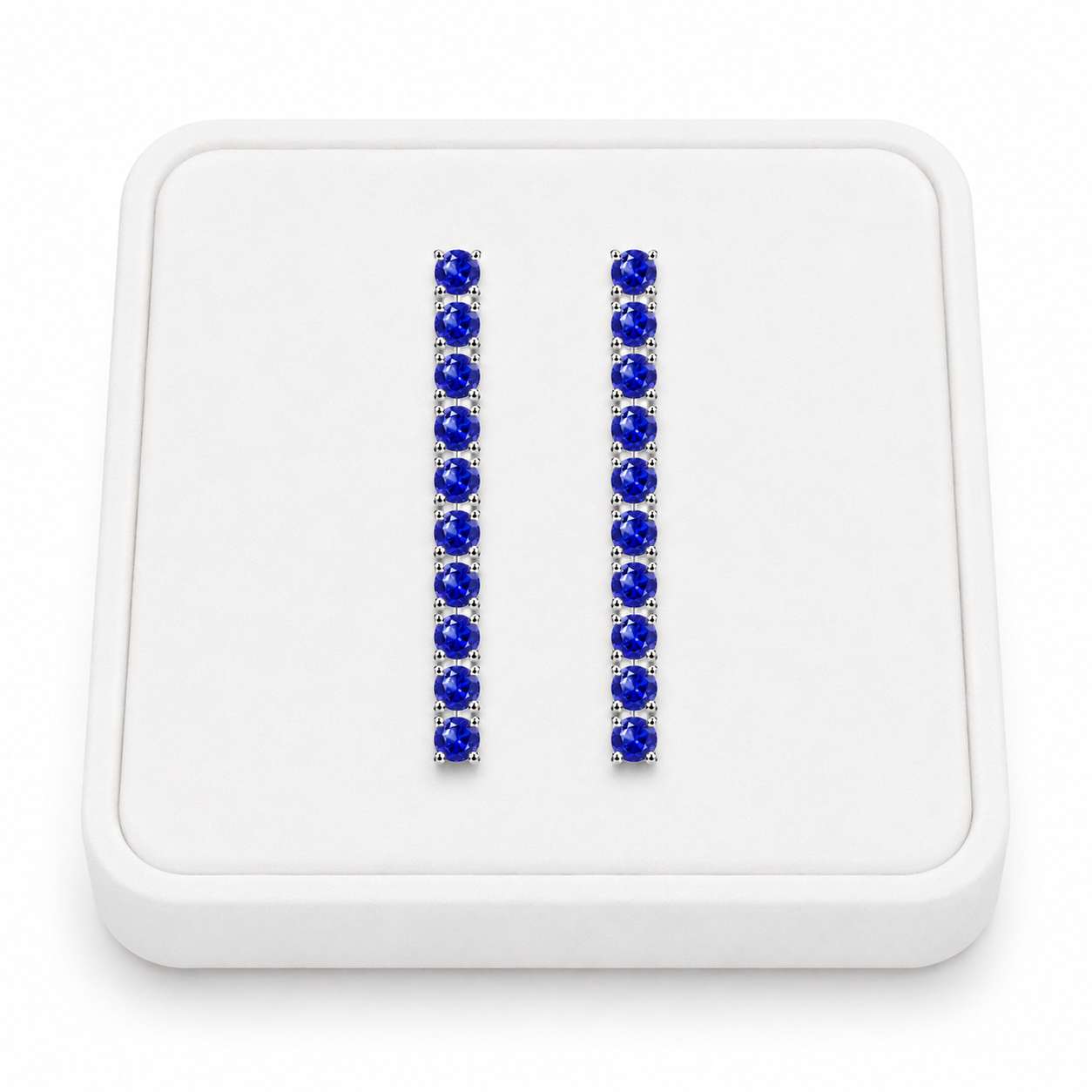 Phimsera natural sapphire dangle earrings displayed on a white velvet jewelry tray against a bright white background