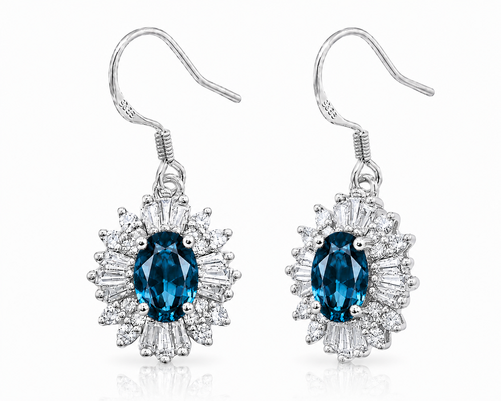 London Blue Topaz floral dangle earrings shown at an angle with deep blue oval gemstones, sparkling halos, and silver fishhooks