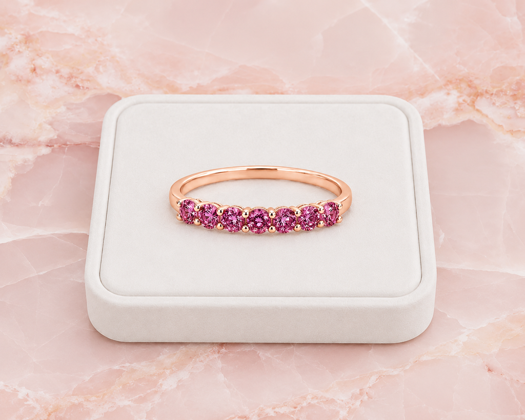 Natural Pink Garnet half eternity ring featuring seven genuine 3mm round pink garnets in rose gold plated 925 sterling silver on a marble background.