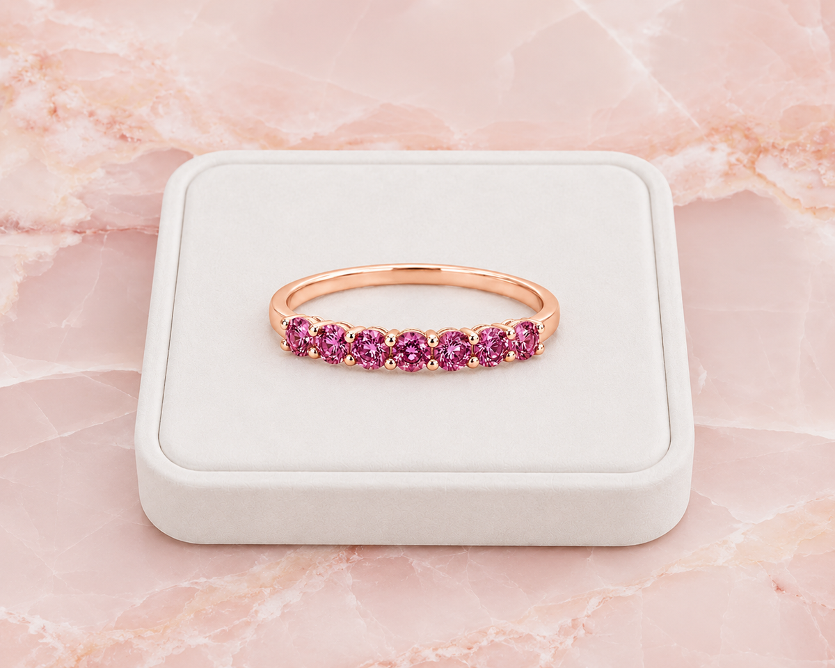 Natural Pink Garnet half eternity ring featuring seven genuine 3mm round pink garnets in rose gold plated 925 sterling silver on a marble background.