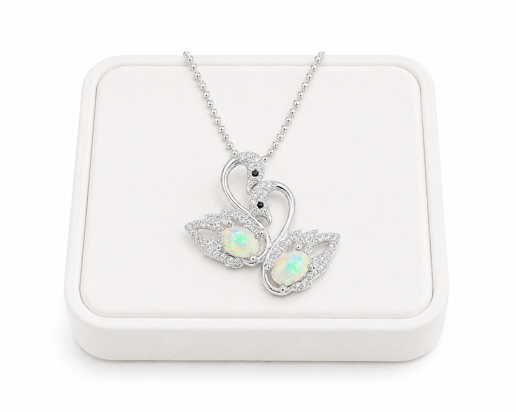 White fire opal double swan necklace with two 5x7mm oval opals in 925 sterling silver over white velvet jewelry tray.