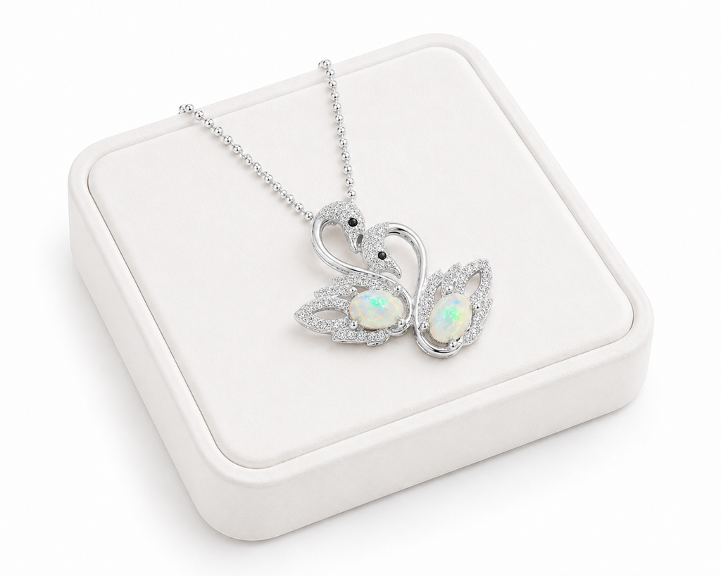 White fire opal double swan necklace with two 5x7mm oval opals in 925 sterling silver over white velvet jewelry tray.