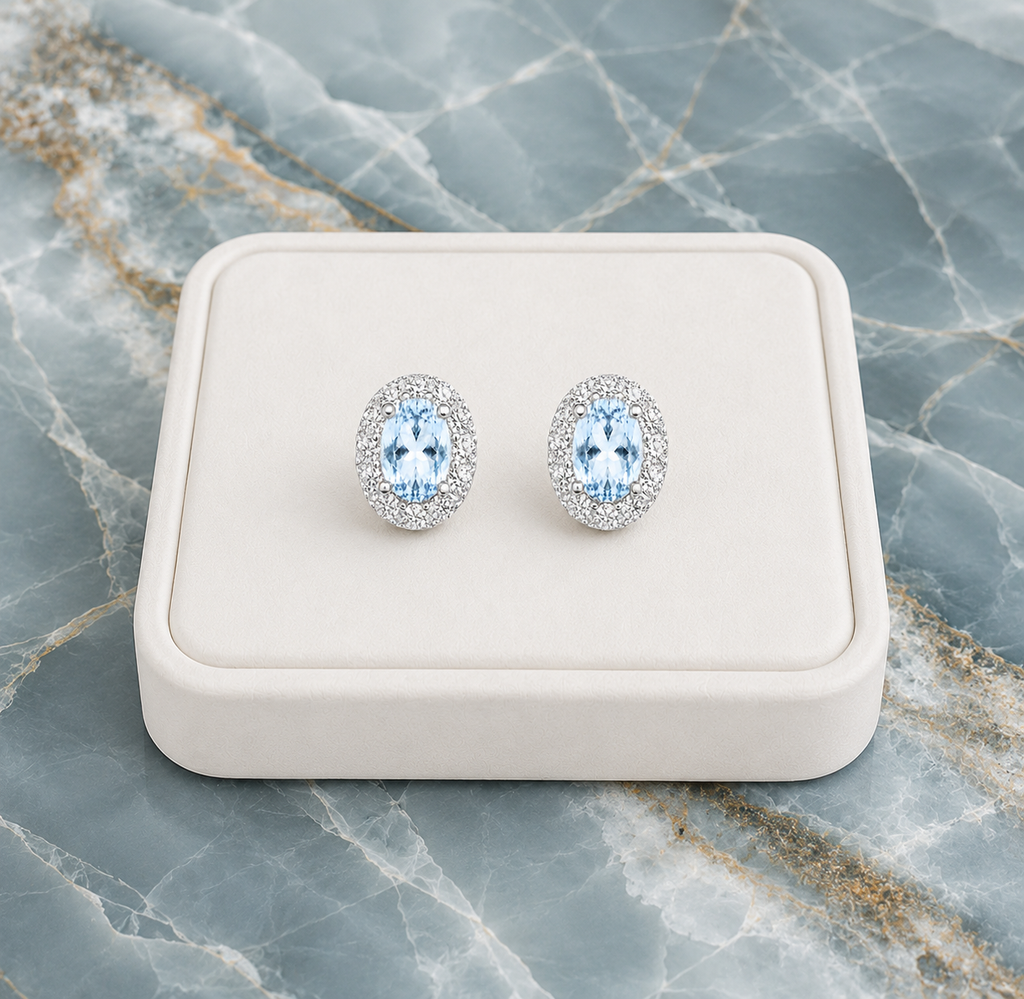 Natural Sky Blue Topaz oval halo earrings displayed on luxury white jewelry tray