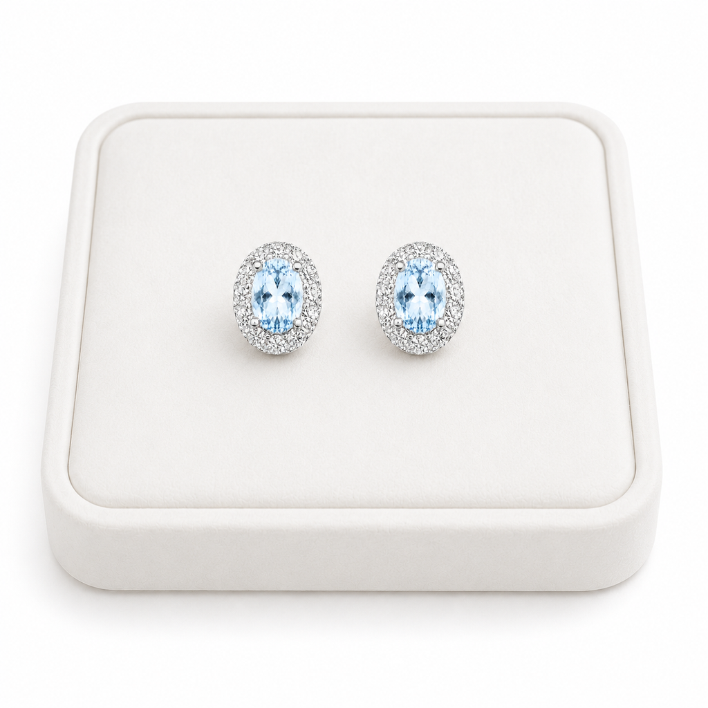 Natural Sky Blue Topaz oval halo earrings displayed on luxury white jewelry tray