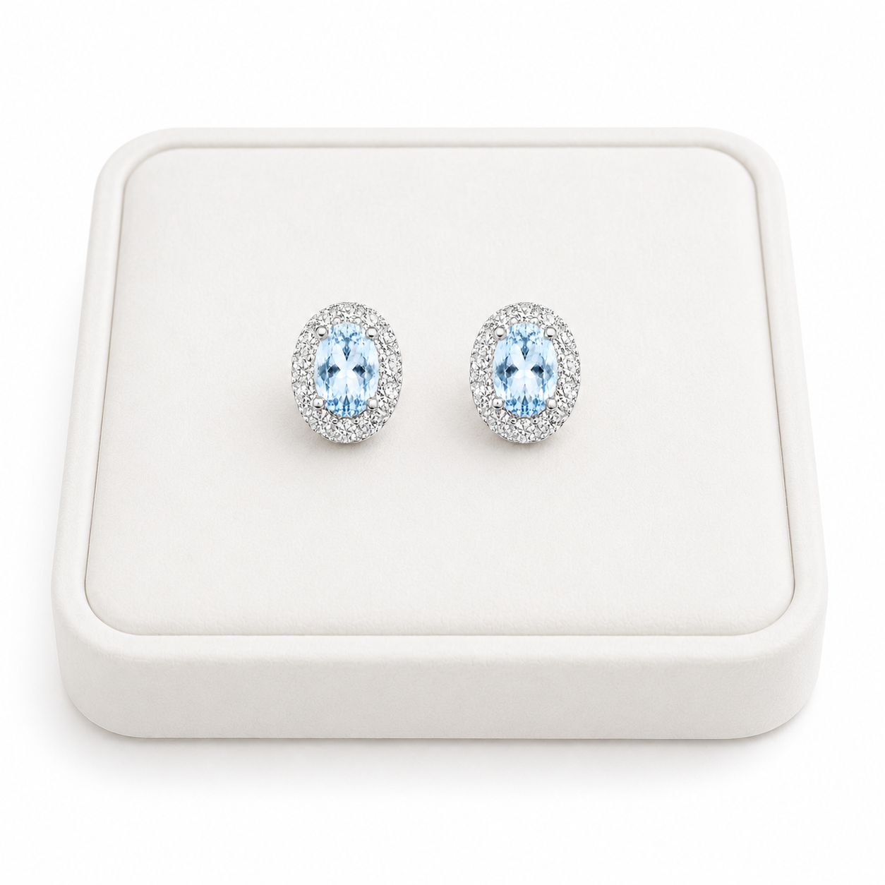 Natural Sky Blue Topaz oval halo earrings displayed on luxury white jewelry tray
