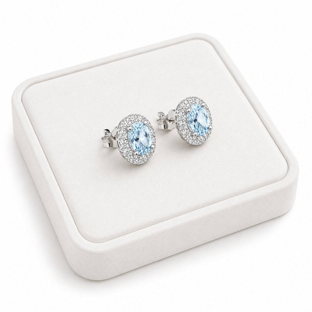 Natural Sky Blue Topaz oval halo earrings displayed on luxury white jewelry tray